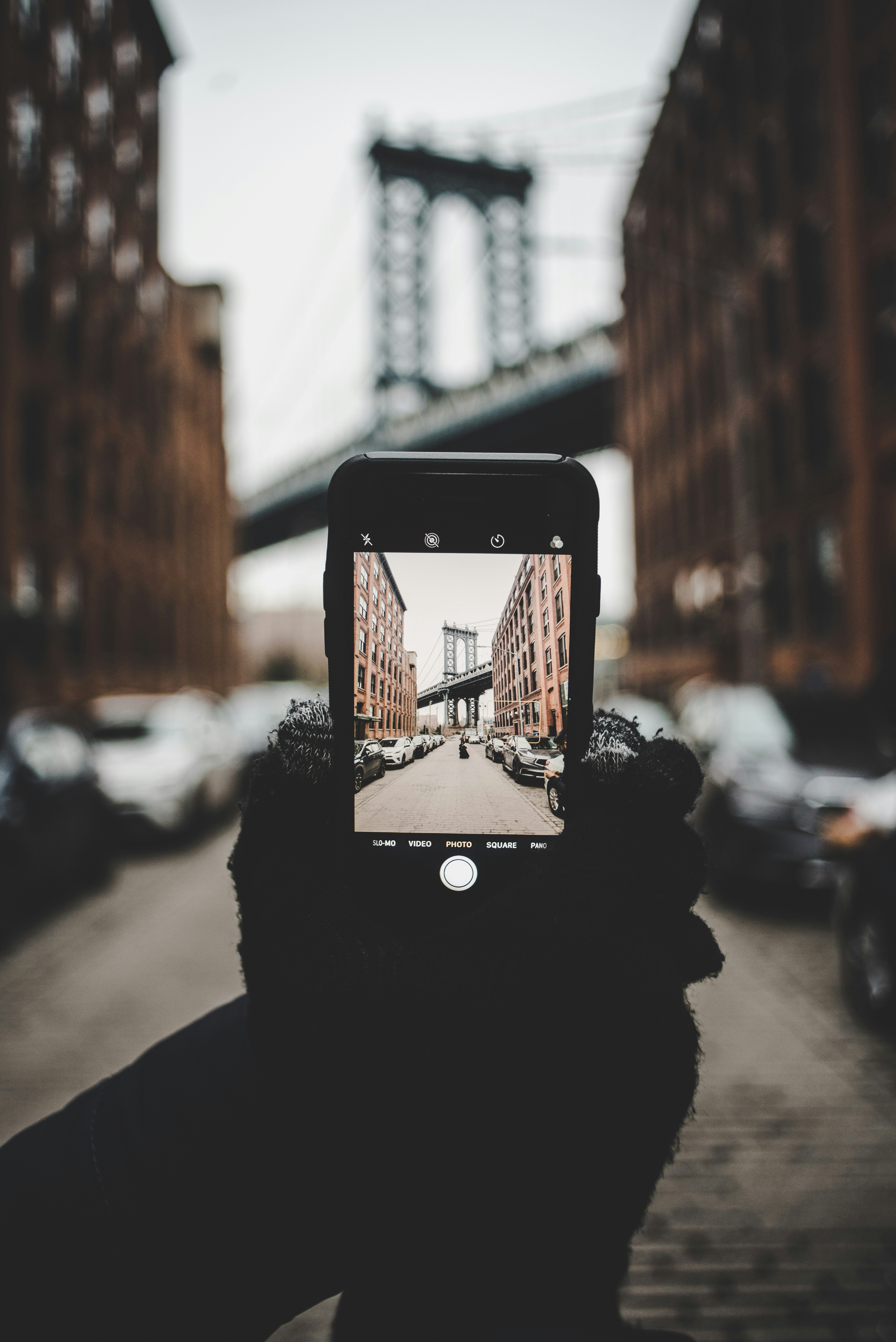 person taking photo of a bridge selective focus photography